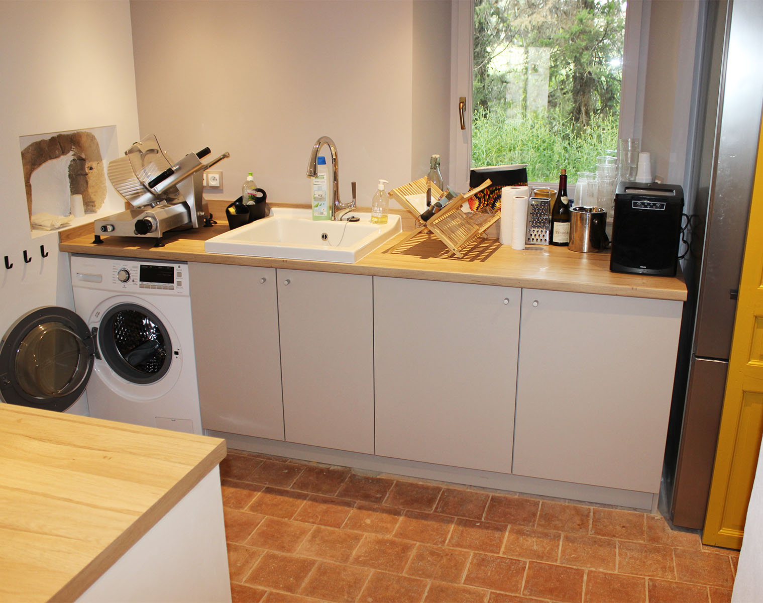 Façades et corps de meuble — Décors gris Cachemire.
Plan de travail et crédence — Décors chêne Pila.
Bouton — Aluminium mat.
Évier — Céramique blanc.
Robinet — Chromé.