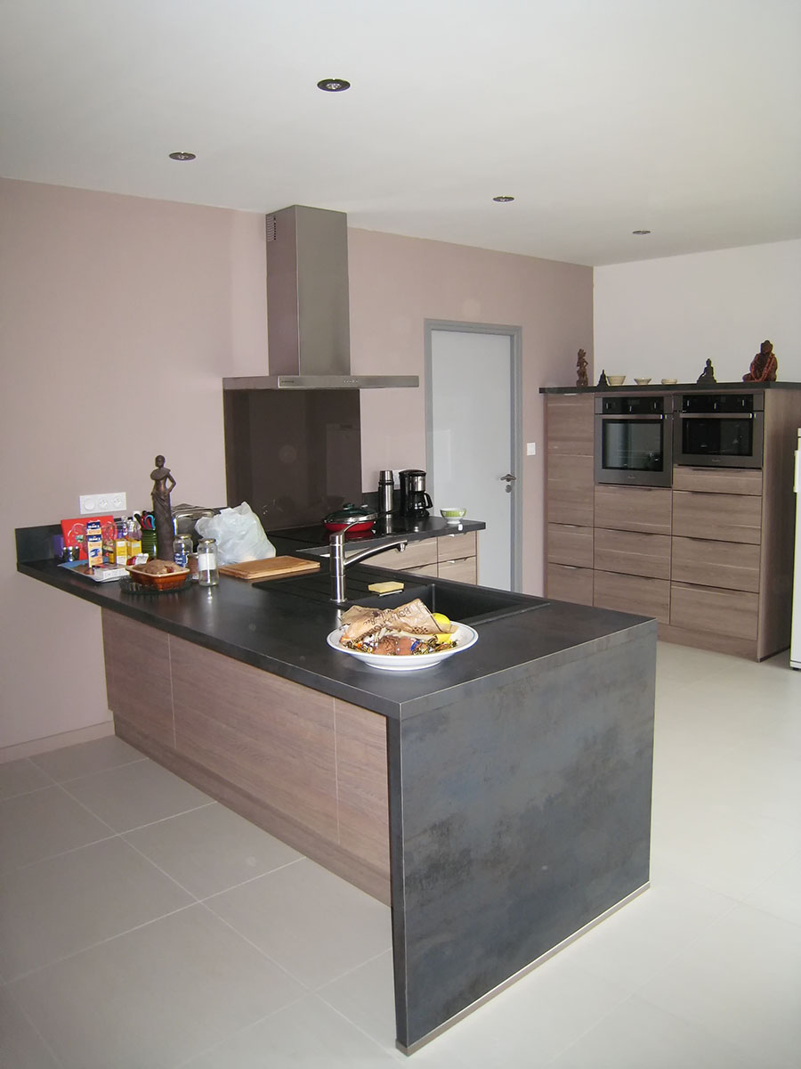 Façades — Décors chêne cendré.
Poignées profil — Inox.
Plan de travail — Décor Métallo-marine.
Crédence — Verre laqué Brown.
Évier encastré — Résine.
Electroménager — Plaque de cuisson, hotte, four, micro-onde, lave-vaisselle, frigo.