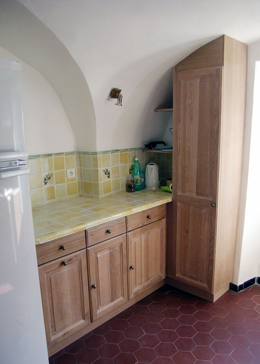 Façade — Chêne massif, verni.
Poignées — Boutons laiton patiné.
Plan de travail — Carrelage provencale.