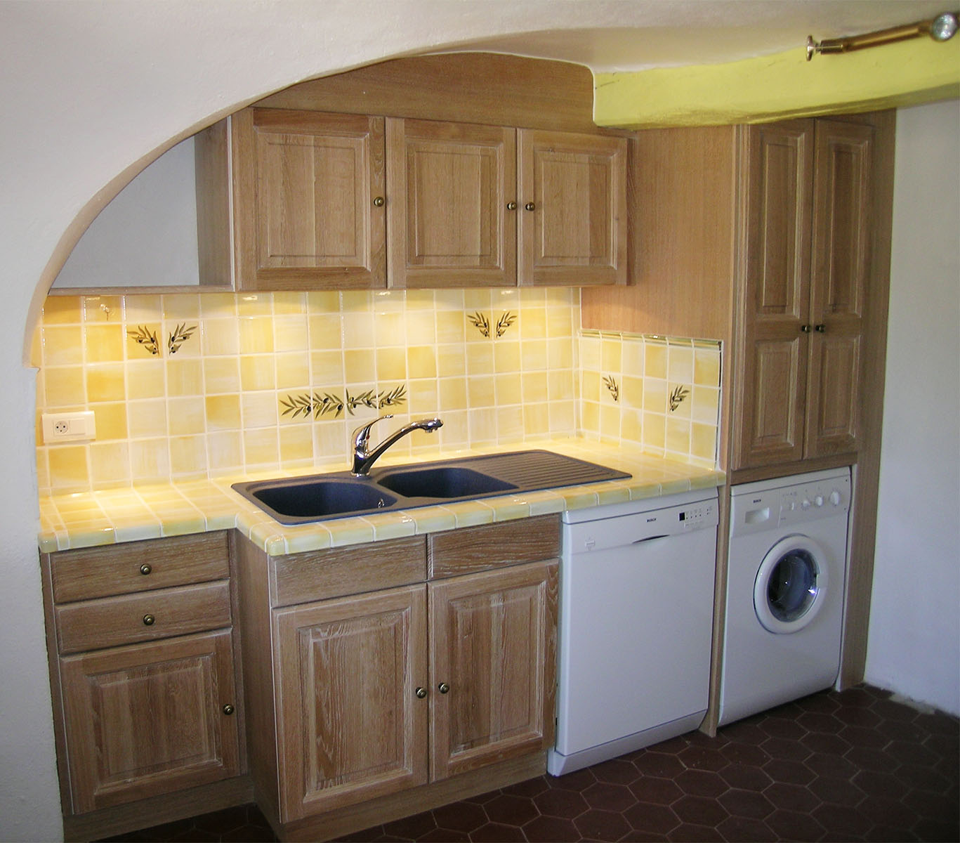 Façade — Chêne cérusé blanc, verni.
Plan de travail — Carrelage provençale.
Evier encastré — Résine.
Electroménager — lave vaisselle, lave linge.