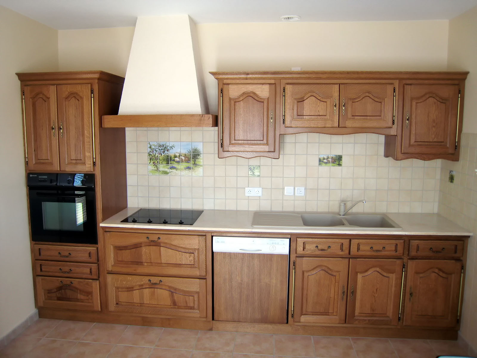 Façade — Chêne, teinté vernis.
Poignées — Serrures et poignées tombantes.
Plan de travail — Pierre de Mareuil.
Evier encastré — Résine Fragranite
Electroménager — Four, Plaque de cuisson, hotte.